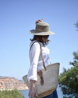 Capazo de palma natural con asas largas para colgar y cierre con hebilla. Cassani made in Spain.