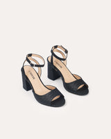 Sandalias en piel trenzada negra atadas al tobillo con hebilla cuadrada y tacón ancho