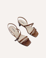 Sandalias asimétricas destalonadas con tiras cruzadas y puntera cuadrada en piel grabada mostaza y con tacón midi de 4,5 cm.