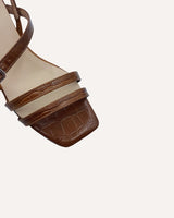 Sandalias asimétricas destalonadas con tiras cruzadas y puntera cuadrada en piel grabada mostaza y con tacón midi de 4,5 cm.